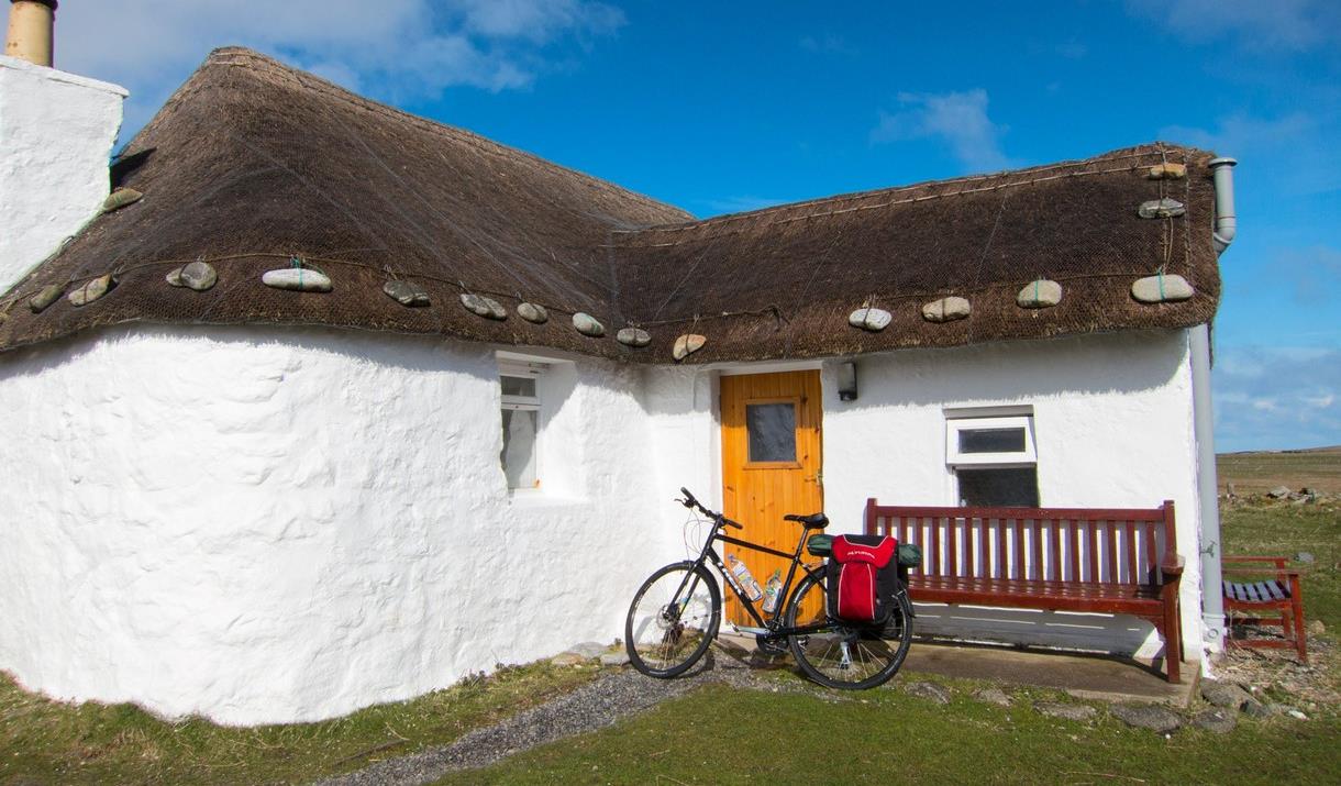 Ticket To Ride white thatched cottage with bike outside