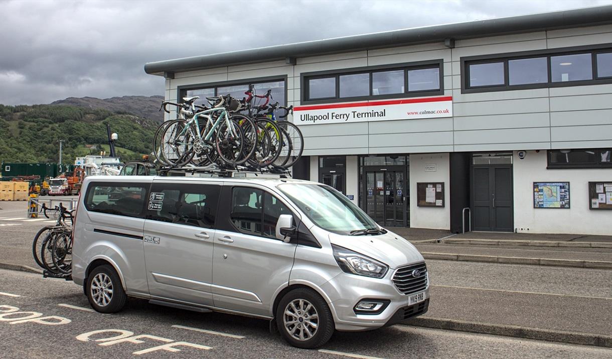 Ticket To Ride van with bikes on roof at ferry terminal