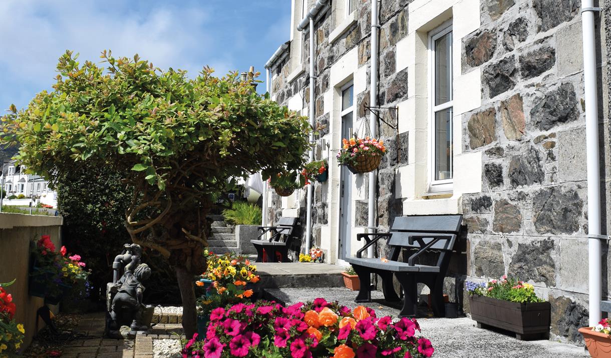 Tigh na Mara, Isle of Barra - stone exterior of the guesthouse with bench and flowers
