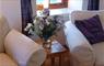 Inside Glaic Cottage with armchairs and display of flowers.