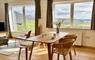Mangersta Steading interior view of dining table and chairs and 2 large windows with views of the Uig Hills and Mangersta coastal cliffs.