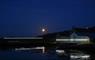 Photo of Taigh Chearsabhagh taken on a dark moonlit evening, showing the tide line lighting installation round the building.